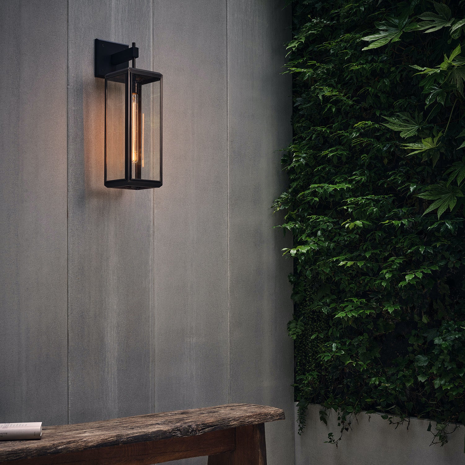 J Adams Lilac Wall Light in bronze with clear glass on a grey concrete wall