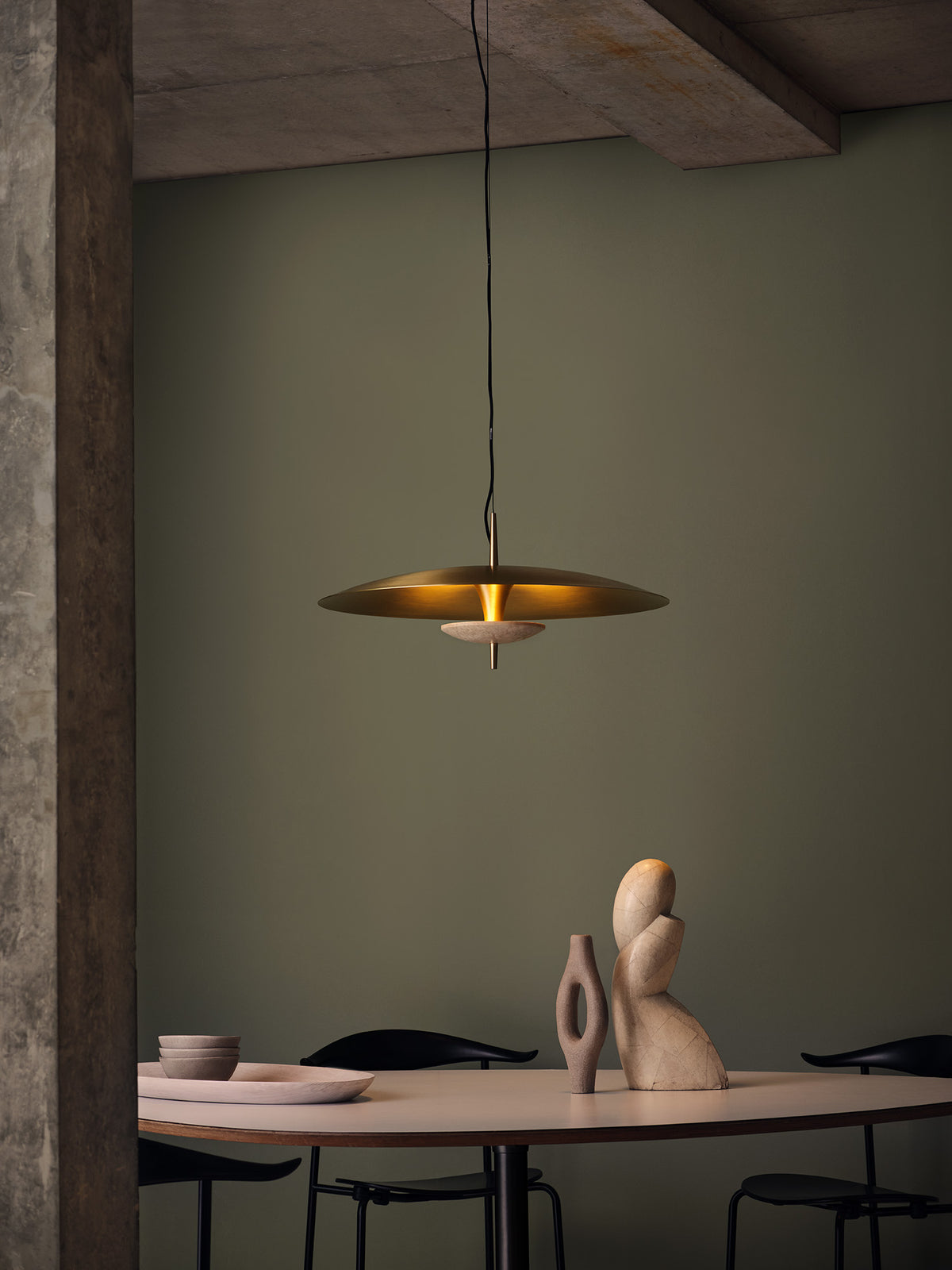 Small Luna Pendant Light in antique brass with travertine disc suspended above modern dining table