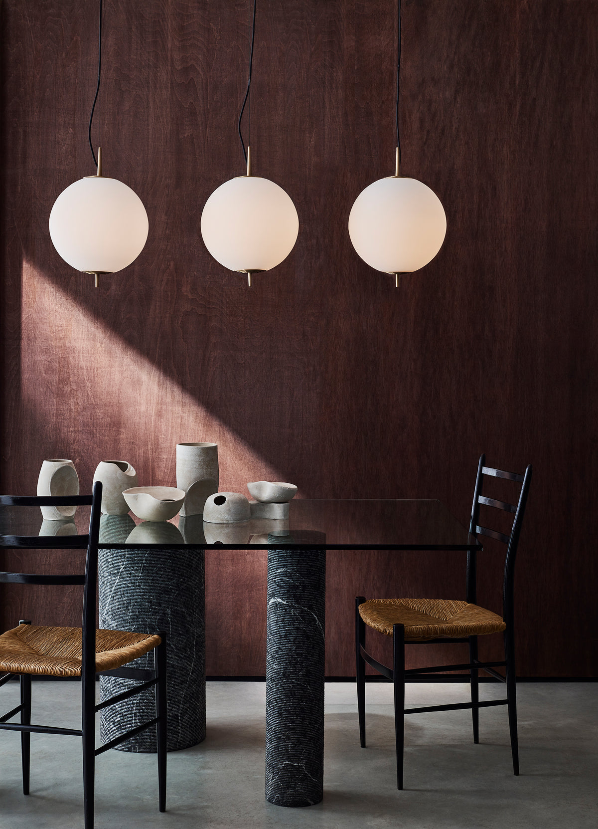 Grouping of three Nova Globe Pendant Lights with wooden panelled backdrop